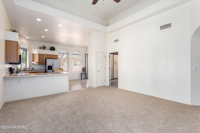 kitchen featuring kitchen peninsula, a wealth of natural light, light colored carpet, and stainless steel fridge