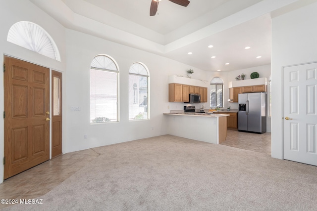 kitchen featuring kitchen peninsula, appliances with stainless steel finishes, light carpet, and ceiling fan