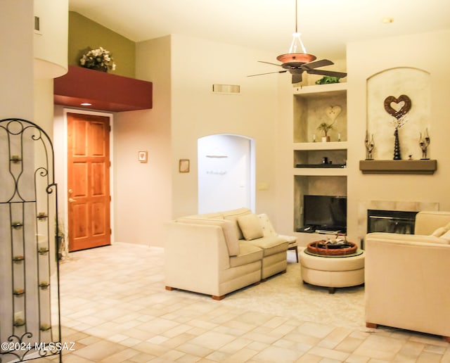 living room with built in shelves, a towering ceiling, and ceiling fan