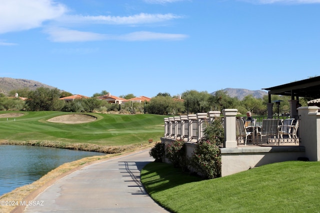 view of property's community with a water and mountain view and a yard