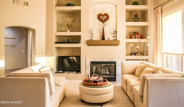 living room featuring built in shelves and a tile fireplace