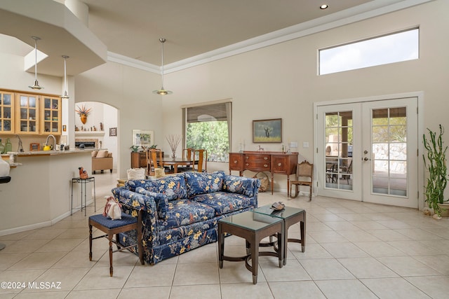 tiled living room featuring crown molding, french doors, and a high ceiling