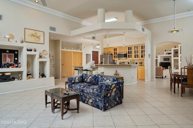 living room featuring a towering ceiling, light tile patterned floors, and ornamental molding