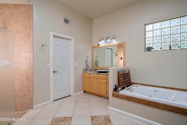 bathroom with tile patterned flooring, vanity, and a relaxing tiled tub