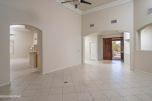 tiled spare room with ceiling fan, a towering ceiling, and crown molding