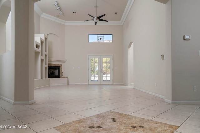 unfurnished living room featuring light tile patterned floors, ornamental molding, and a high ceiling