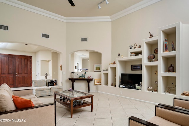 tiled living room with crown molding, built in features, and a high ceiling