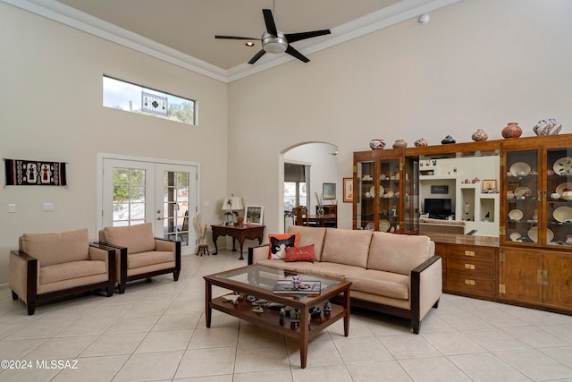 tiled living room featuring ceiling fan, french doors, a towering ceiling, and crown molding