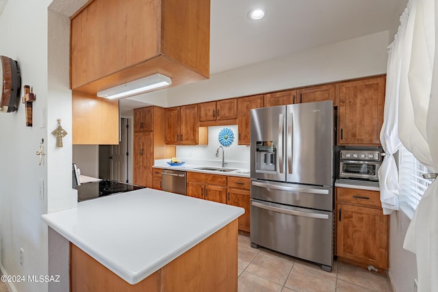 kitchen featuring light countertops, stainless steel appliances, brown cabinetry, and a sink