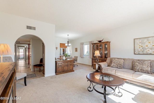 living room with arched walkways, light carpet, and visible vents