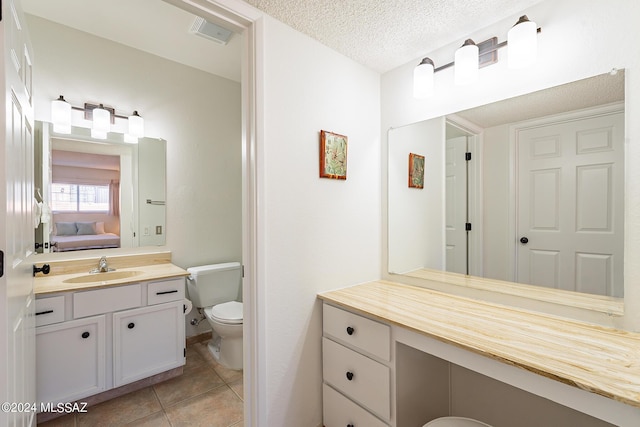 bathroom featuring a textured ceiling, tile patterned flooring, vanity, toilet, and connected bathroom