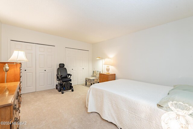 bedroom with multiple closets and light colored carpet