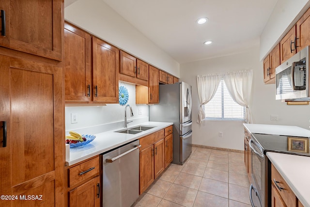 kitchen featuring light countertops, a sink, brown cabinets, and stainless steel appliances