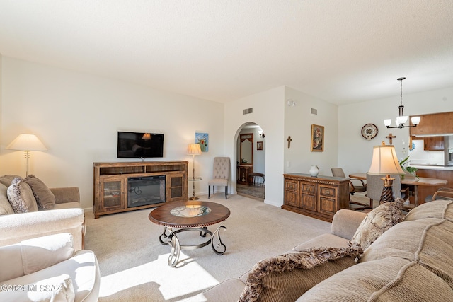 living room featuring carpet floors, visible vents, an inviting chandelier, baseboards, and arched walkways