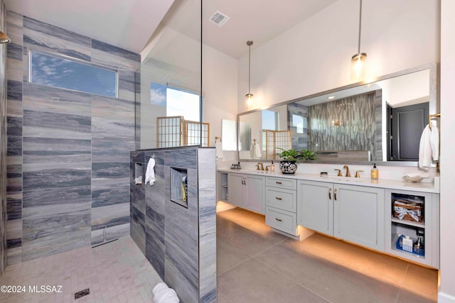 bathroom featuring a high ceiling, vanity, a shower, tile patterned floors, and tile walls