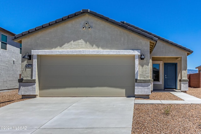 ranch-style home featuring stucco siding, an attached garage, and driveway