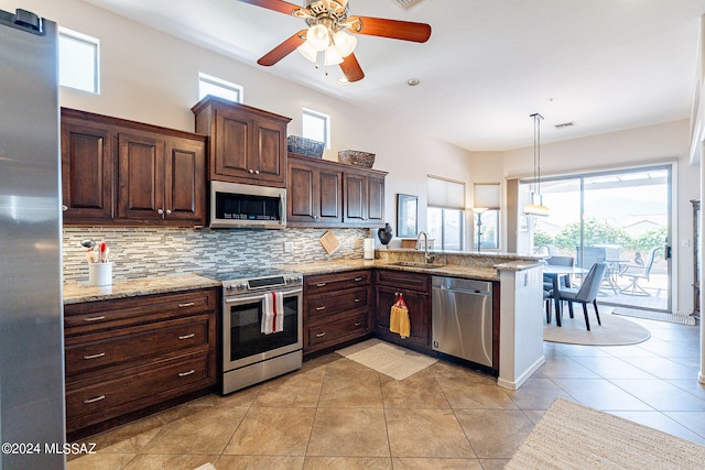 kitchen with hanging light fixtures, kitchen peninsula, stainless steel appliances, sink, and tasteful backsplash