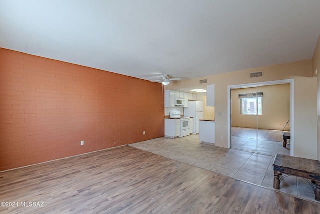 unfurnished living room featuring brick wall, light hardwood / wood-style flooring, and ceiling fan