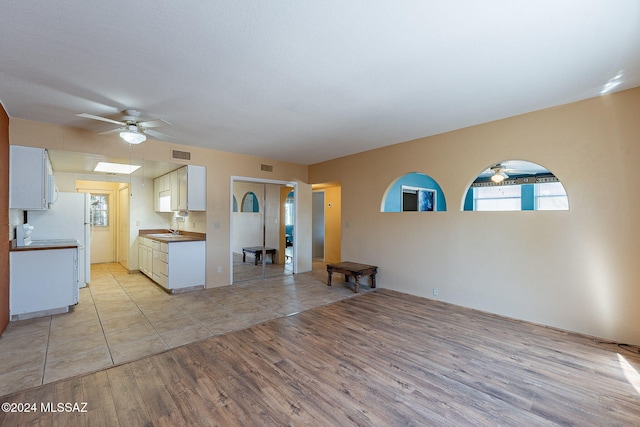 interior space featuring sink, light hardwood / wood-style flooring, white cabinetry, and ceiling fan