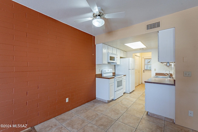 kitchen with white cabinets, light tile patterned flooring, sink, brick wall, and white appliances