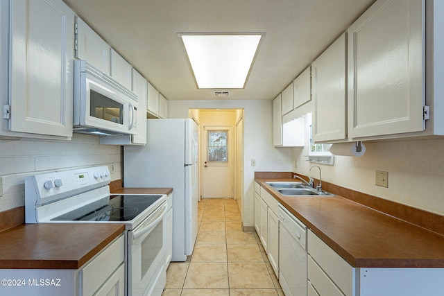 kitchen featuring sink, white cabinetry, white appliances, and light tile patterned floors