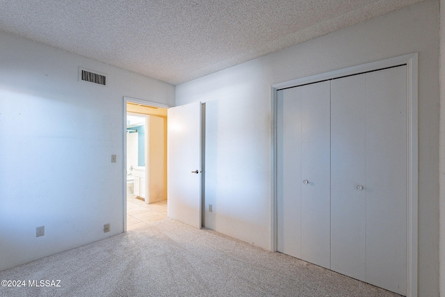 unfurnished bedroom featuring a closet, light carpet, and a textured ceiling