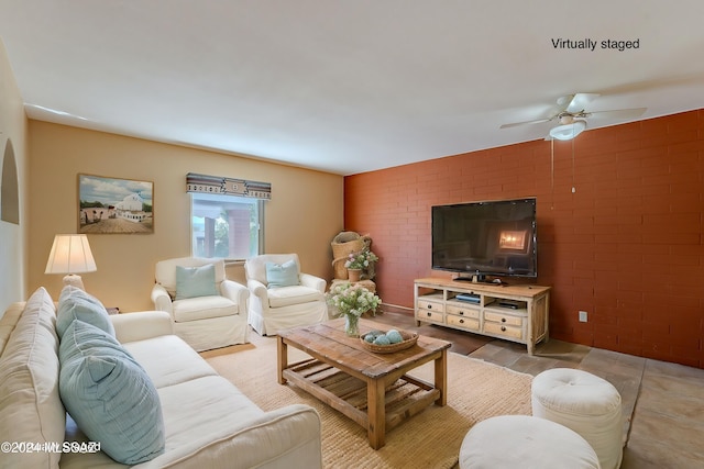 living room featuring brick wall and ceiling fan