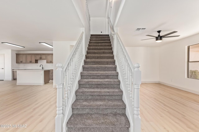 stairs with sink, hardwood / wood-style flooring, and ceiling fan