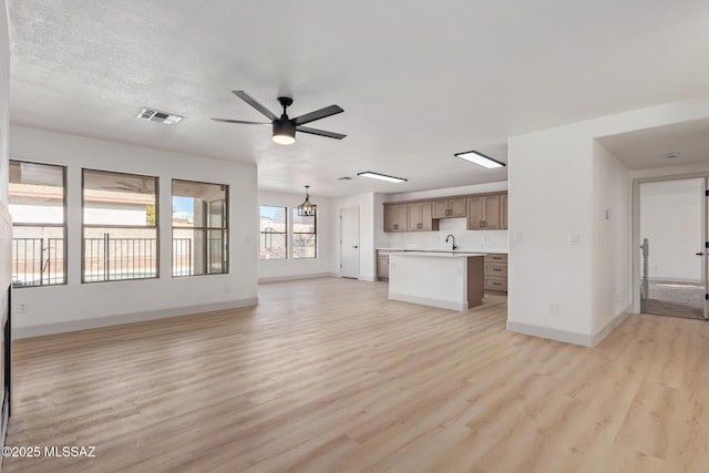 unfurnished living room featuring sink, a textured ceiling, light hardwood / wood-style flooring, and ceiling fan