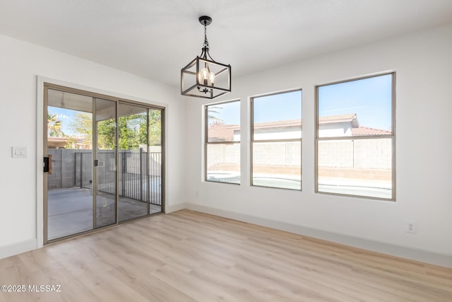 unfurnished dining area with a chandelier and light hardwood / wood-style flooring