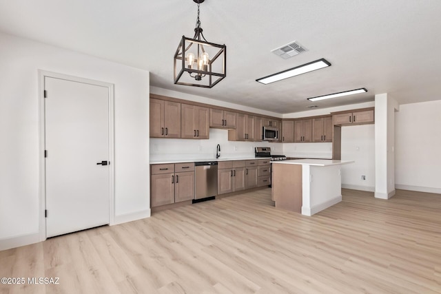 kitchen with decorative light fixtures, light wood-type flooring, a kitchen island, a notable chandelier, and stainless steel appliances