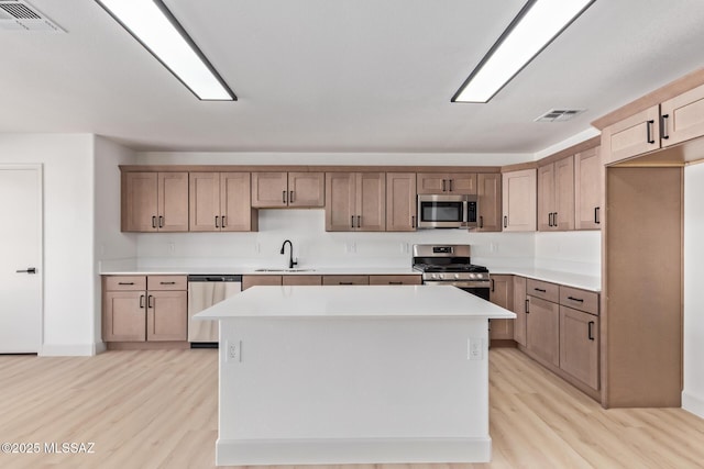 kitchen featuring appliances with stainless steel finishes, sink, a kitchen island, and light hardwood / wood-style flooring