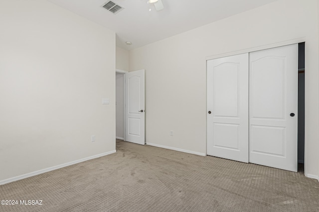 unfurnished bedroom featuring ceiling fan, light colored carpet, and a closet