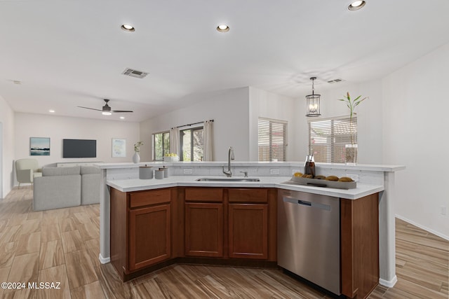 kitchen featuring a center island with sink, sink, hanging light fixtures, light hardwood / wood-style flooring, and stainless steel dishwasher