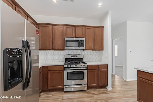 kitchen with appliances with stainless steel finishes, light wood-type flooring, and tasteful backsplash