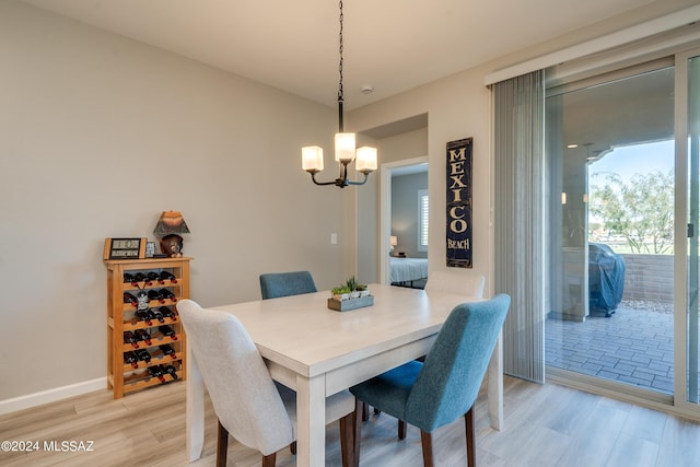 dining area with light hardwood / wood-style floors and an inviting chandelier