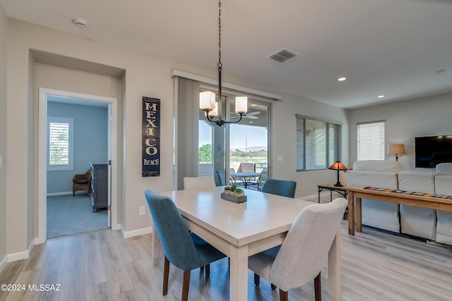 dining area with light wood-type flooring and an inviting chandelier