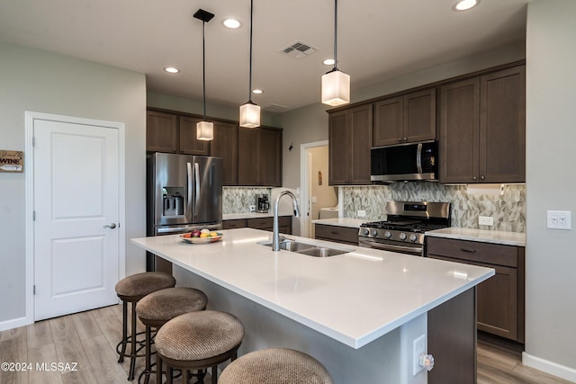 kitchen featuring sink, an island with sink, hanging light fixtures, and appliances with stainless steel finishes