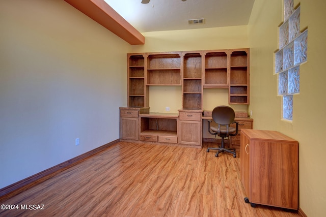 unfurnished office featuring light hardwood / wood-style floors, built in desk, and ceiling fan