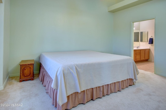 bedroom with ensuite bath, light carpet, and sink