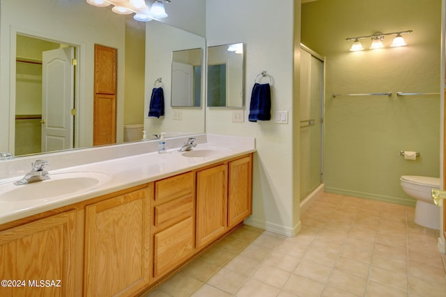 bathroom with toilet, a shower with shower door, vanity, and tile patterned flooring