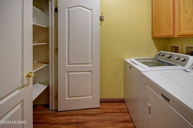 clothes washing area featuring cabinets, washing machine and dryer, and dark hardwood / wood-style flooring