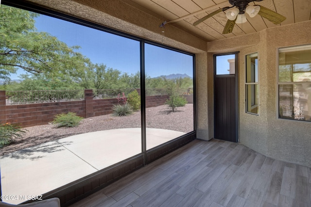 unfurnished sunroom with a healthy amount of sunlight, wooden ceiling, and ceiling fan