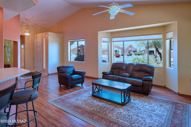 living room featuring a healthy amount of sunlight, hardwood / wood-style flooring, ceiling fan with notable chandelier, and vaulted ceiling