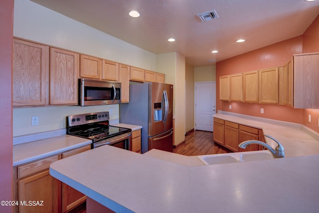 kitchen with appliances with stainless steel finishes, light hardwood / wood-style flooring, sink, and light brown cabinetry