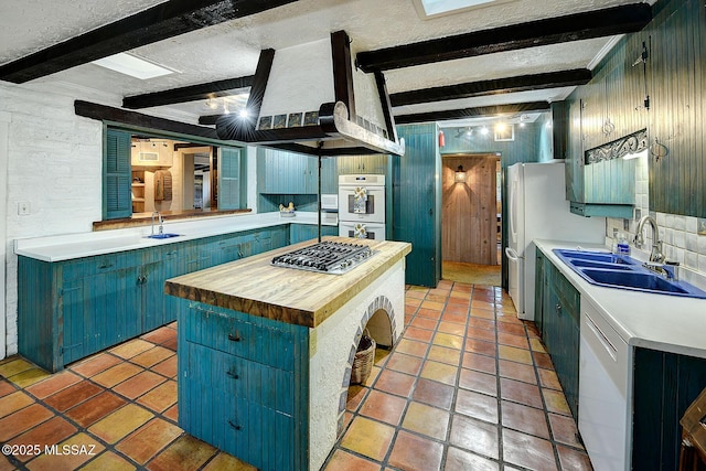 kitchen with beamed ceiling, a center island, sink, and appliances with stainless steel finishes