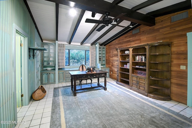 home office featuring light tile patterned flooring, ceiling fan, lofted ceiling with beams, and wood walls