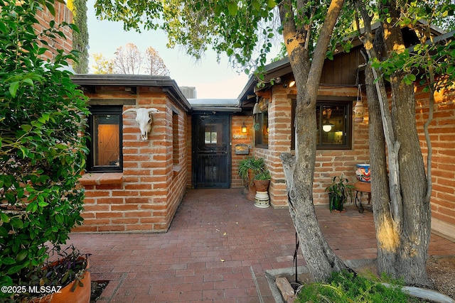 view of exterior entry with a patio area