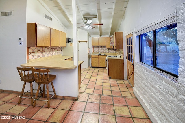 kitchen with sink, white gas stove, vaulted ceiling with beams, tasteful backsplash, and a kitchen breakfast bar