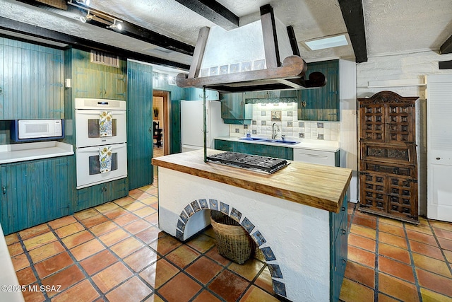 kitchen with beamed ceiling, white appliances, sink, and exhaust hood